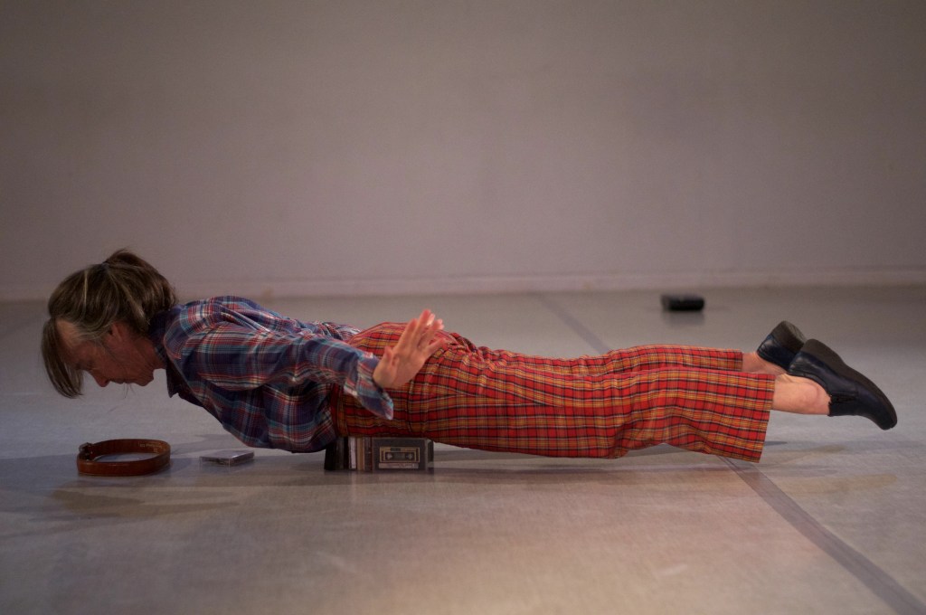 Linda Austin lying prone, belly on cassete boxes, a few inches off the ground