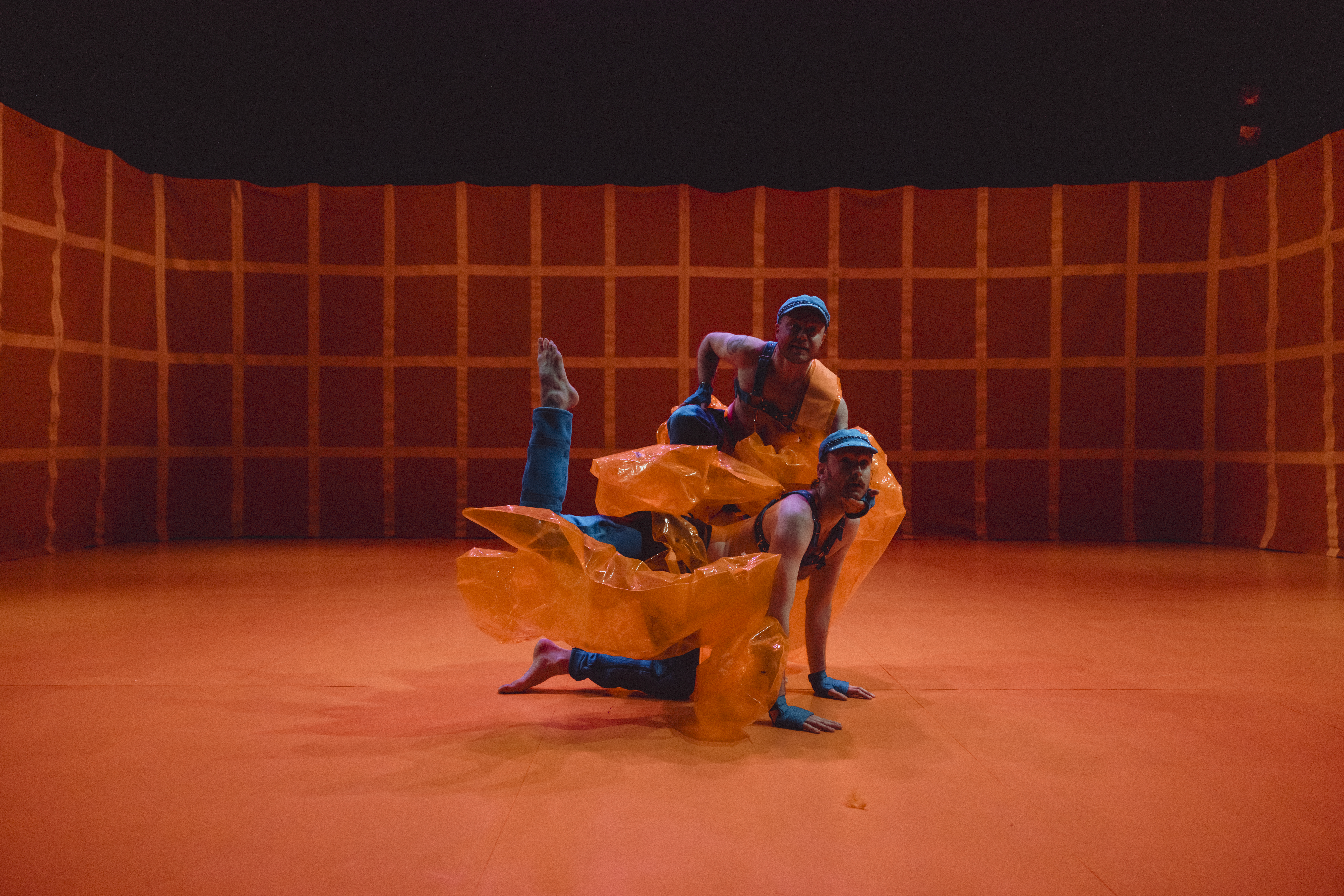two dancers in a formation in orange light and a grid in the background